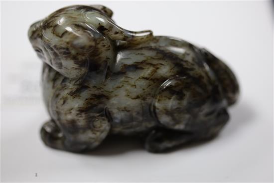 A Chinese pale grey and black jade recumbent figure of a lion-dog, length 8.3cm